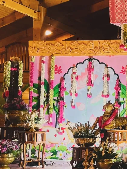 A side view of the naming ceremony stage, showing the depth and detail of the decor. The combination of the wooden structure, pink backdrop, and hanging flowers creates a truly magical setting.