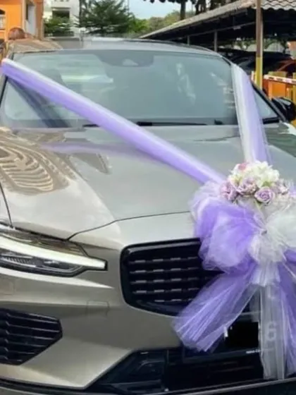 A minimalist car decoration using a large purple and white ribbon bow. This is a great option if you prefer a simple, non-floral design for your wedding car.