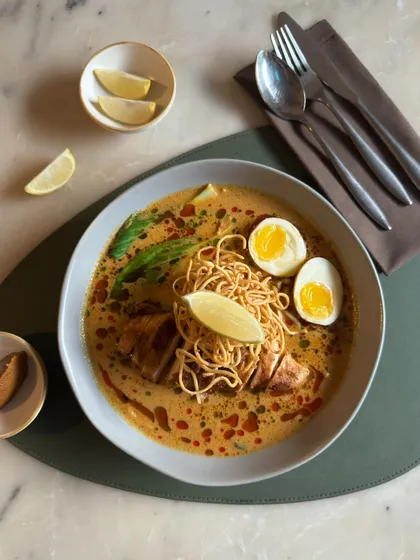 A beautifully presented bowl of our Khao Soi, garnished with fresh lime and crispy noodles.