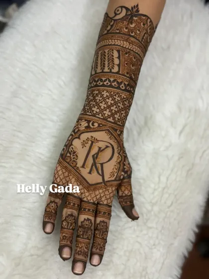 A single-hand view of an intricate bridal design. It showcases the beautiful 'KR' initial monogram and the detailed geometric and floral patterns that extend up the arm.