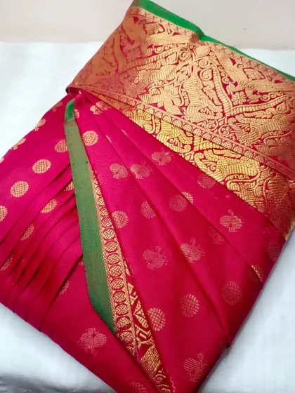 A bright pink silk saree with gold butis, with customized pleats.