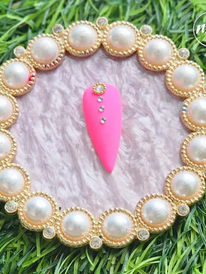A bold pink matte nail with simple, elegant rhinestone placement. This student work shows that sometimes, less is more.