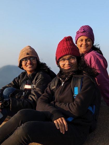 Friends bundled up in winter hats, enjoying the chilly morning at the top of Skandagiri.