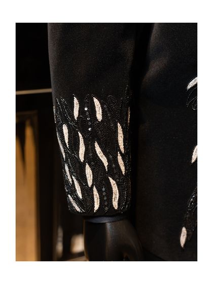 The cuff detail of the black velvet blazer. The intricate beadwork and sequins are applied by hand, a process that ensures every piece is unique and exquisitely finished.