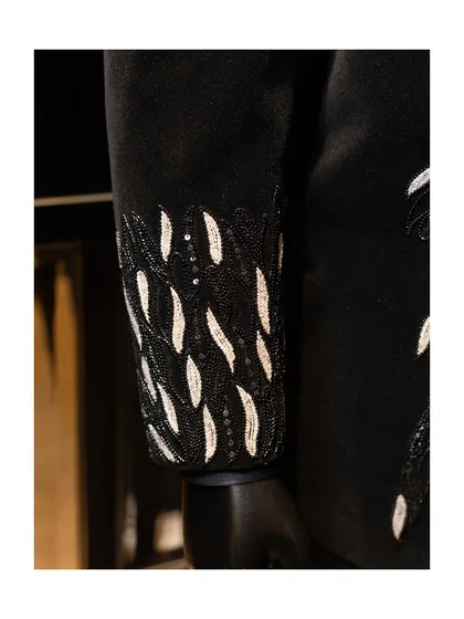 The cuff detail of the black velvet blazer. The intricate beadwork and sequins are applied by hand, a process that ensures every piece is unique and exquisitely finished.