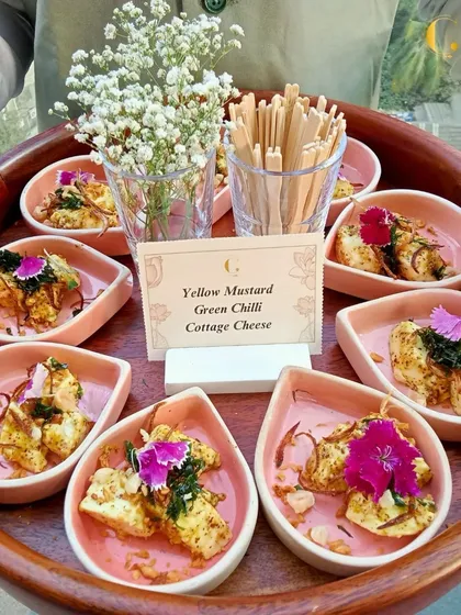 A tray of our Yellow Mustard Green Chilli Cottage Cheese appetizers, garnished with edible flowers. This dish is a perfect example of our ability to elevate traditional Indian flavours.