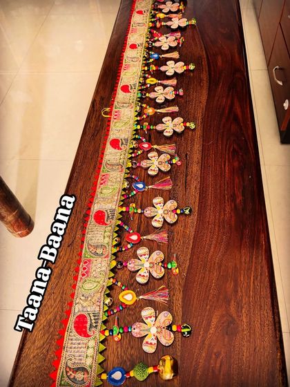 Another angle of the 'Taana Baana' toran, capturing the playful arrangement of its dancing flowers and handcrafted mirror garlands.