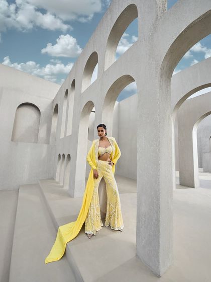 A breathtaking yellow sharara set, fully embroidered and paired with a flowing cape that billows like a prism-cast aura. This ensemble is a dance of radiance and grace.