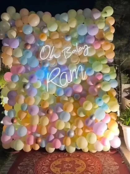 A vibrant 'Oh Baby' backdrop made entirely of pastel-colored balloons. The custom neon sign with the baby's name, Ram, adds a personal and modern touch.