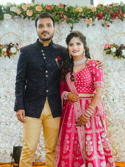 A perfect portrait of a well-dressed couple. The groom's navy Jodhpuri with beige trousers complements the bride's stunning pink lehenga.