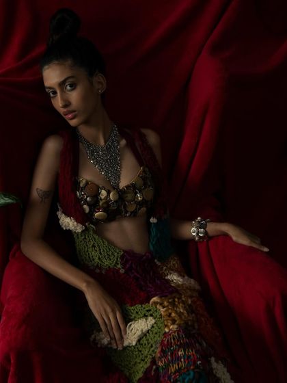 A direct and powerful pose against a dramatic red backdrop. This shot highlights the intricate details of the designer's work.