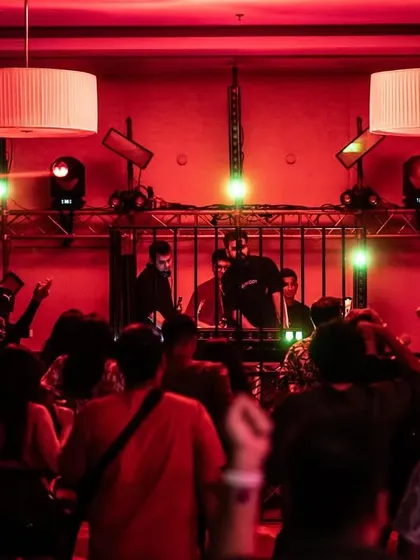 A wide shot of the party, showing the crowd dancing under red lights as the DJ performs. This captures the scale and excitement of our ballroom events.