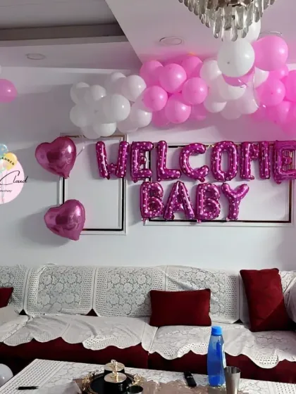 A simple and sweet 'Welcome Baby' girl decoration in a living room with pink and white balloons.