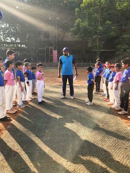 A coach addresses a lineup of young cricketers on the pitch, setting the strategy and motivating them before a match.