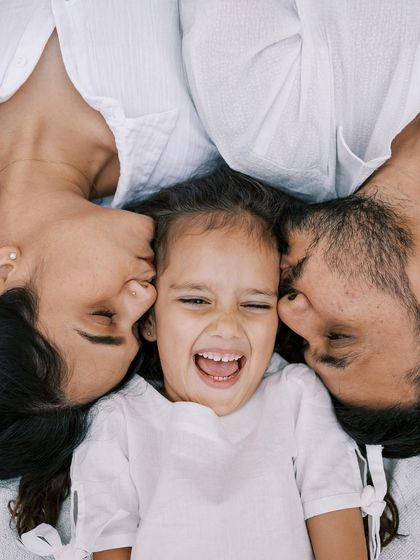 A "kiss sandwich" for a laughing little girl. A perfect example of a fun, interactive family portrait.