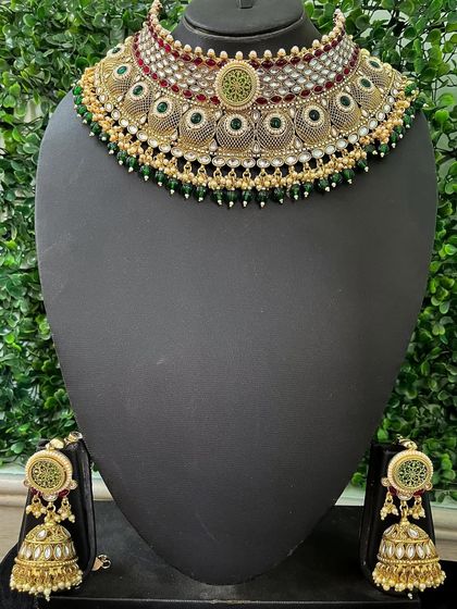 This rental choker set features intricate filigree work with green enamel and matching jhumkas. It's a great choice for a bride who appreciates detailed craftsmanship.