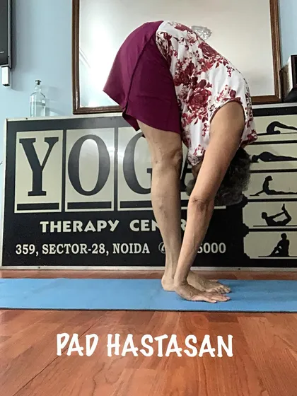 A demonstration of Padahastasana, a standing forward bend that stretches the back of the legs and improves posture.