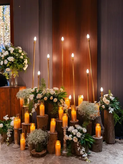 A rustic decor element for the reception, with candles on wooden logs and white floral arrangements.