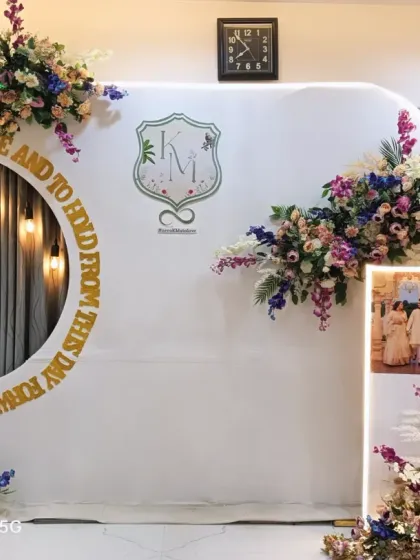 A modern and sophisticated backdrop for an engagement. It features a clean white panel with a circular cutout, a custom couple's monogram, and beautiful floral arrangements.