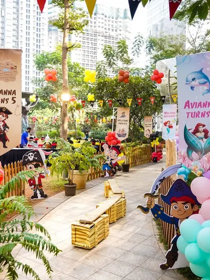 A wide shot of the outdoor party area, showing the themed decor and activity stations spread across a lush garden path.