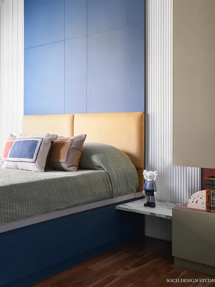 A shot of the kids' bed with its colorful cushions and a tall blue headboard, creating a fun and cozy sleeping area.