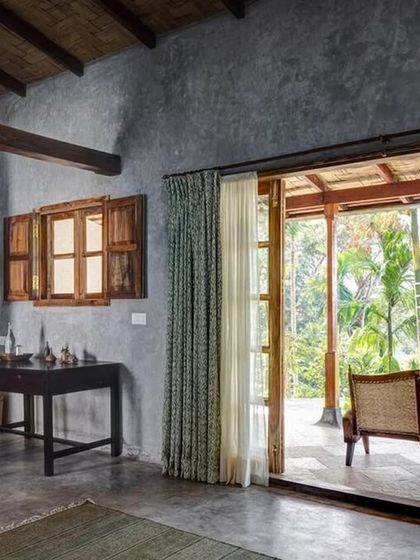 The interior of the Garden Suite's green room, with its cool grey cement walls and a door opening onto a private veranda.