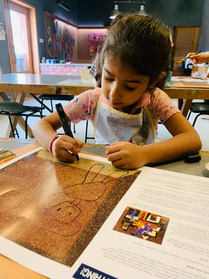A young girl outlines her figures, showing great concentration and control.