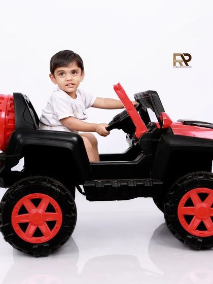 A toddler enjoys a ride in a toy jeep, looking ready for an adventure. These playful portraits are a great way to capture the energy and fun of the toddler years.