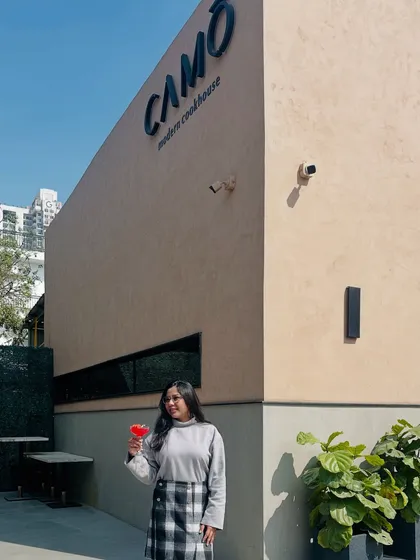 Standing outside the modern cookhouse, Camo Noida, with a drink in hand, giving a full view of its unique architecture.