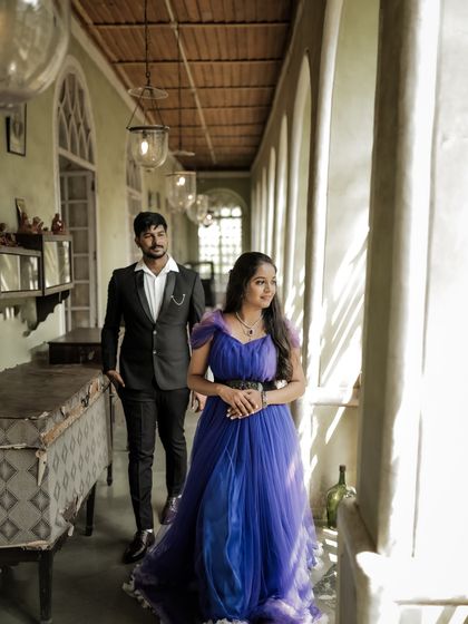 A candid-style pre-wedding shot in a beautiful, sunlit corridor. The purple gown with its ruffled trail adds a touch of romance and elegance.
