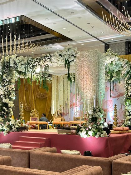A side view of the white and green lotus-themed mandap, showing the depth of the floral arrangements and the soft, layered draping. This perspective highlights the balance between the structured stage and the organic flow of the flowers.