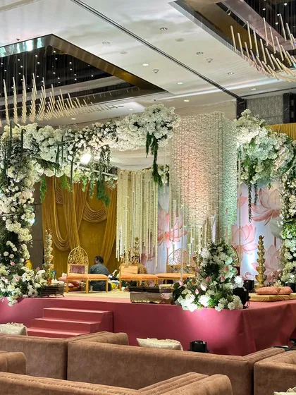 A side view of the white and green lotus-themed mandap, showing the depth of the floral arrangements and the soft, layered draping. This perspective highlights the balance between the structured stage and the organic flow of the flowers.