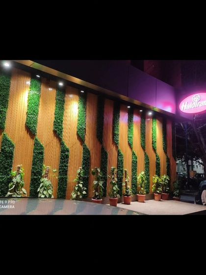 For commercial clients, I create eye-catching facades that attract customers. Here is an installation for a Haldiram's outlet, where I integrated vertical green panels with wood-style slats for a bold, branded exterior.