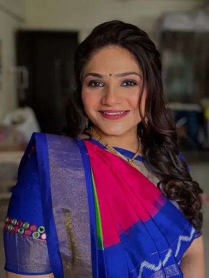 A stunning client in a traditional silk saree. The makeup is soft and glowing, with a subtle smokey eye that complements the rich blue and pink of her outfit.