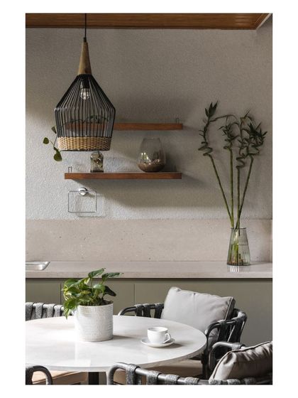 A detail of the outdoor pantry and dining area, showing the mix of concrete-finish countertops, wooden shelves, and a woven pendant light.
