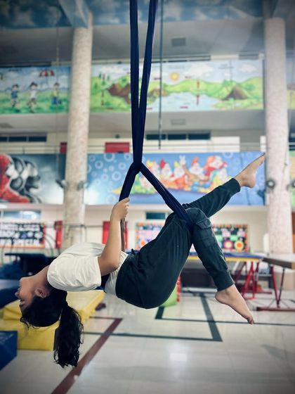 A student relaxes into a gentle backbend supported by the silk, a move that helps improve posture and spinal flexibility.