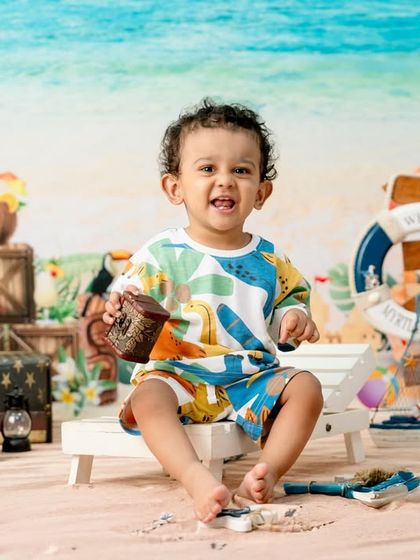 A fun and vibrant beach-themed shoot. This happy toddler is enjoying a day at the "seaside" in my studio, complete with sand, shells, and surfboards.