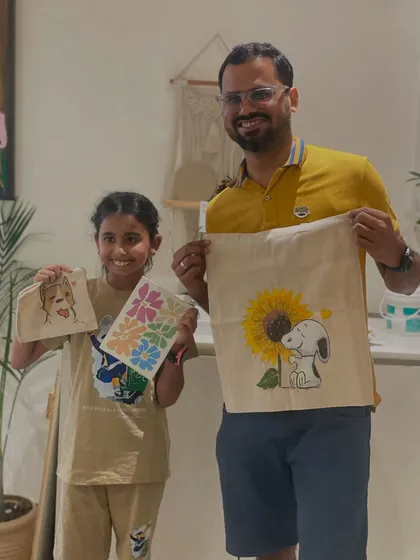 A father and daughter duo proudly present their finished tote bags. Creating functional art like this is a fun way to make something you can use every day.