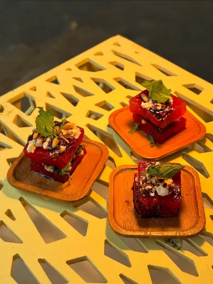 Another view of our watermelon and feta stacks, garnished with mint and nuts. The presentation on small wooden plates adds a rustic, elegant touch.