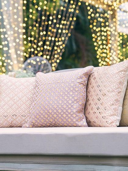 Cushions with varied textures in soft pink and gold add comfort and style to the lounge seating. These details contribute to the overall luxurious feel of the event.