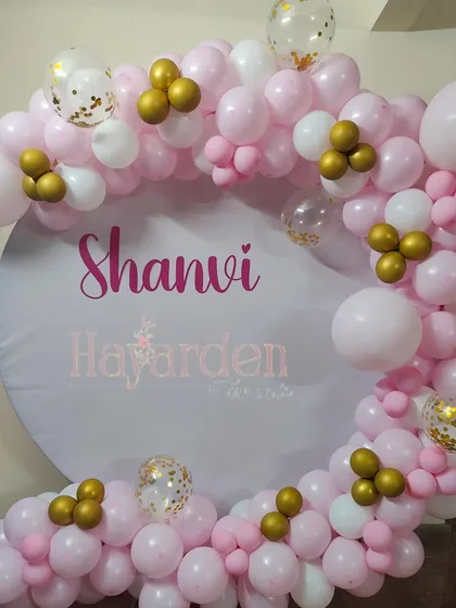 A simple and sweet circular backdrop with a custom name and a partial balloon garland in pink and white.