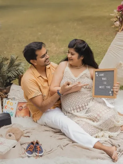 The couple shares a laugh while holding a sign that reads "Can't wait to meet you". This photo perfectly captures the joy and anticipation of their pregnancy.