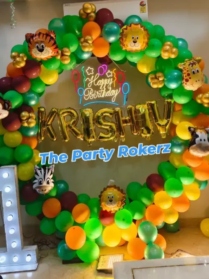 A closer look at the jungle-themed balloon arch, showing the different shades of green, orange, and brown balloons, along with cute animal foil balloons like a monkey, lion, and zebra.