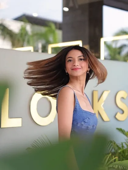 A client outside the salon, her freshly styled and coloured hair blowing in the wind, showcasing its movement and shine.