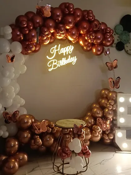 A 5th birthday party with a rose gold and white balloon ring, butterfly accents, and a "5" marquee number.