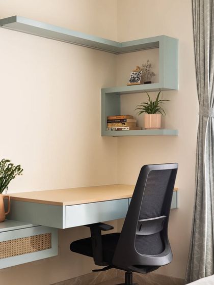 The study nook in this master bedroom features a floating desk and L-shaped shelving in a calming pastel blue, creating a serene and organized workspace.