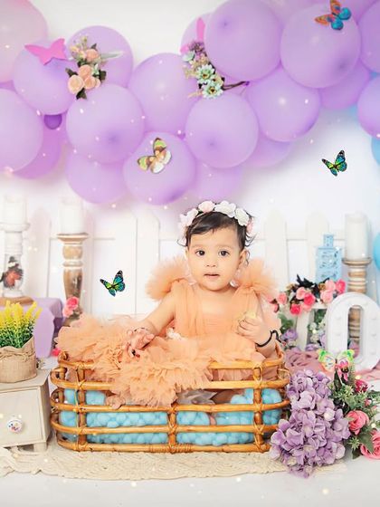 A beautiful portrait for a beautiful one-year-old. Our butterfly garden setup, complete with a wicker basket and colorful balloons, creates a perfect scene for a first birthday.