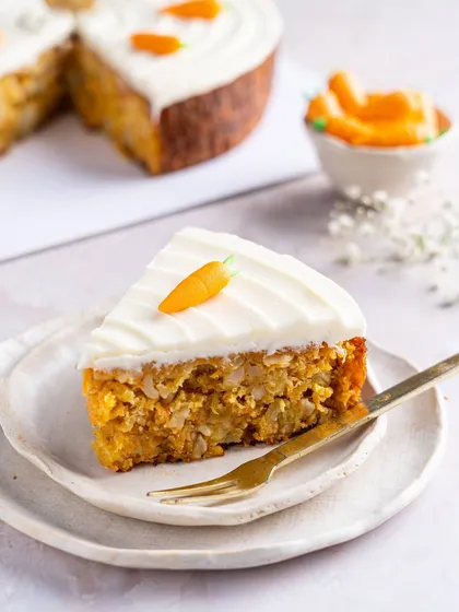A close-up slice of our Old Fashioned Carrot Cake, highlighting its dense, moist texture filled with grated carrots and nuts. The thick cream cheese frosting makes it an irresistible classic.