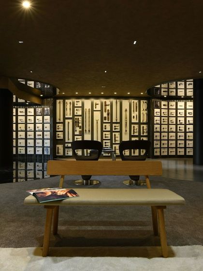 A display wall in the Gala hardware showroom, where door handles are presented as works of art. The dark, moody lighting and curved walls create a gallery-like feel.