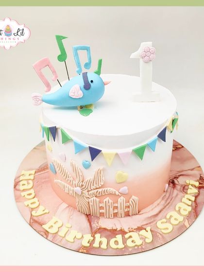 A sweet Mickey Mouse-themed cake for a first birthday. This design features Baby Mickey, a blue balloon, and peacock feathers for a unique and adorable touch.